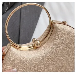 Detailed close-up of champagne gold clutch with lace texture and circular metal handle