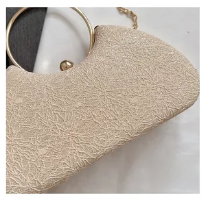 Detail view of champagne gold evening bag featuring intricate lace texture and ring handle