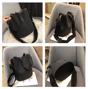Detail view of black bucket bag with white contrast stitching and gold hardware accents