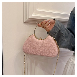 Pink lace evening bag with golden round handle and chain strap in close-up detail