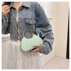 Detail of mint green clutch bag with embossed texture and golden circular handle