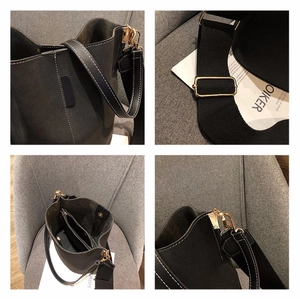 Detail of black bucket bag with contrast stitching, wide strap and gold hardware