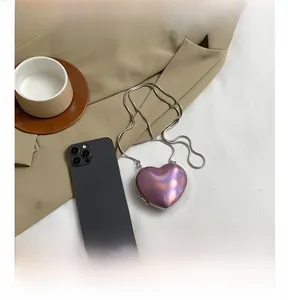 Vue détaillée montrant la petite taille du sac violet en forme de cœur à côté d'un mobile