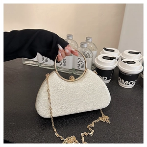 Close-up of white lace texture evening bag with golden ring handle and spherical lock