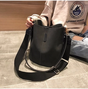 Detail of dark grey bucket bag with contrast stitching and wide woven shoulder strap