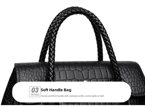 Close-up of black crocodile pattern leather bag featuring a woven handheld strap detail
