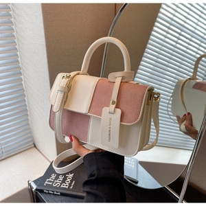 Detail of a beige and pink contrast handbag featuring a lock closure and handle