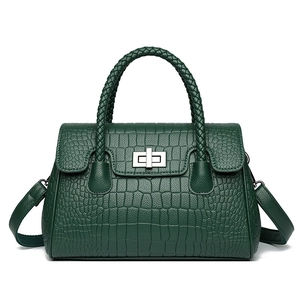 Dark green crocodile embossed handbag with woven handle and metal twist lock on white background
