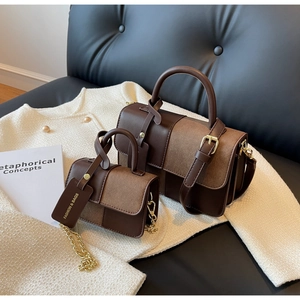 Detail of two-tone brown patchwork handbags with gold hardware and suede texture