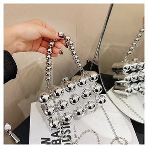 Detail of silver spherical bead handbag with metallic finish and long chain shoulder strap
