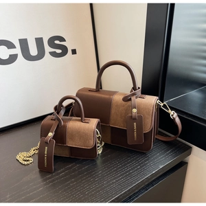 Detail of color-block leather handbags with fashion tags and metal chain straps