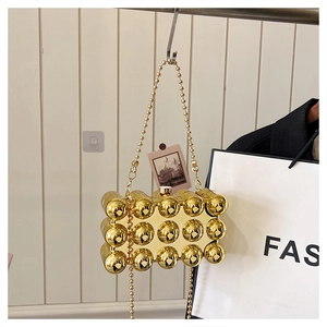 Detail of gold metallic clutch bag with 3D spherical studs and a delicate bead chain