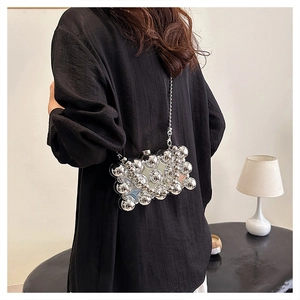 Detail of silver metallic clutch with bubble texture and chain strap on a model