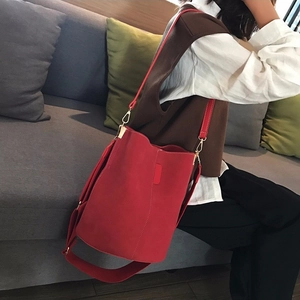 Minimalist red bucket bag with wide fabric strap and golden hardware in lifestyle setting