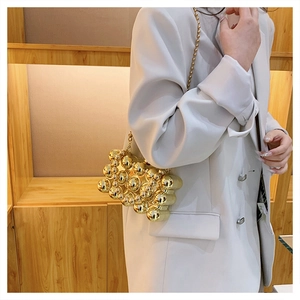 Detail of elegant gold spherical bead clutch bag with metallic chain and luxury texture