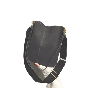 Minimalist black bucket bag with white contrast stitching and adjustable wide strap
