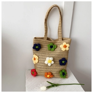 Macro detail of straw woven tote featuring colorful 3D handmade crochet flower patterns