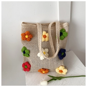 Detail of hollow-out mesh crochet tote bag with colorful 3D floral knitting accents