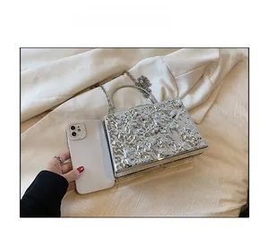 Silver metallic box clutch with metal chain and ring handle compared to smartphone size