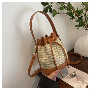 Detail of woven straw bucket bag showing leather drawstring closure and golden hardware