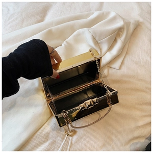 Detailed top view of gold hardshell clutch bag with open black interior and chain strap