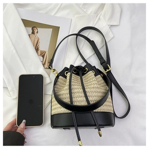 Detail of contrast bucket bag with woven texture, leather base and black drawstring closure