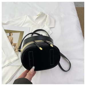 Detail of woven straw bucket bag with black leather stitching and gold hardware