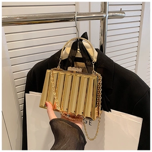 Detail of gold acrylic box clutch featuring textured pleated design and metal handle