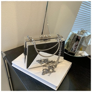 Close-up of silver mirror box bag with snake handle and pyramid stud closure detail