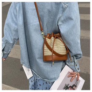 Casual crossbody woven bucket bag with brown leather trim shown on shoulder