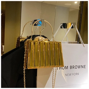 Detailed view of a gold evening box bag with vertical pleated texture and metal handle