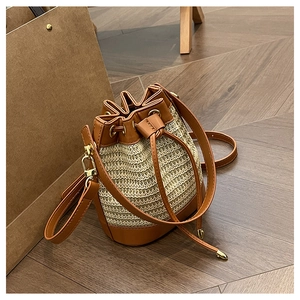 Detail of hand-woven straw bucket bag with brown leather drawstring and gold metal hardware