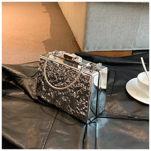 Detail of silver box clutch with hammered texture and pyramid studs on black leather