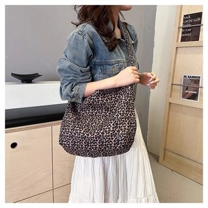 Detail of leopard print canvas shoulder bag worn by model with denim jacket