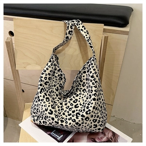 Detailed texture of leopard print canvas hobo bag hanging on a light wood chair