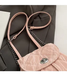 Detail of pink quilted shiny shoulder bag with silver metal twist lock and chain strap
