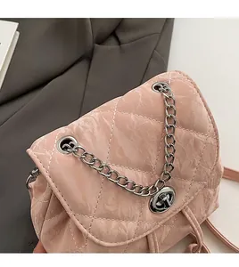 Macro shot of silver metal chain strap and round clasp on quilted pink leather bag