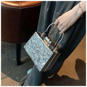 Close-up of silver box clutch with crinkle texture, ring handle and chain strap