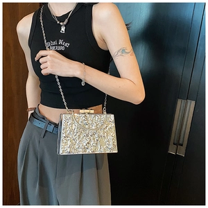 Macro shot of metallic evening clutch with lava texture and golden chain strap detail