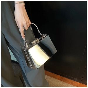 Detail of silver mirror hard shell box bag with metallic handle and chain strap