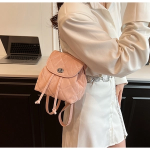 Close-up of pink quilted backpack with silver twist lock and chain strap details