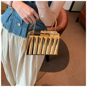 Close-up of golden evening box bag featuring vertical pleated texture and metal chain
