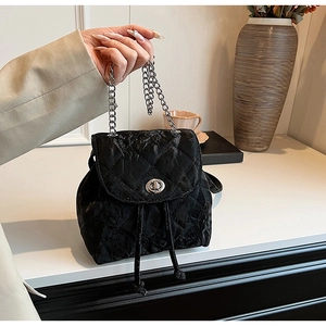 Detail of black quilted backpack with silver twist lock and chic metal chain handle
