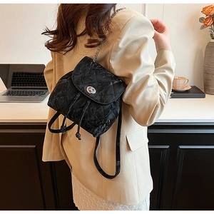 Detailed view of the black quilted chain backpack with silver-tone twist lock closure