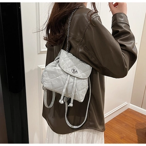 Detailed back view of a light gray quilted mini backpack with silver chain strap on model