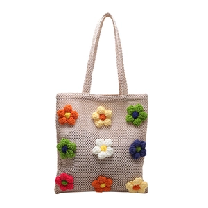 Handmade crochet tote bag with colorful 3D floral decorations and woven shoulder straps