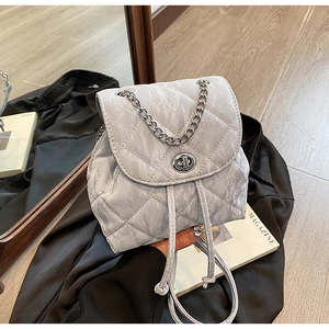 Detail of grey quilted backpack featuring marble texture, chain strap, and silver twist lock