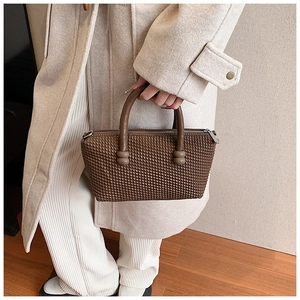 Close-up of dark brown woven texture handbag with round handles and metal zipper detail