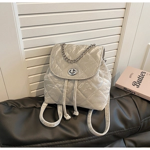Detail of silver metallic quilted backpack with turn-lock closure and chain handle