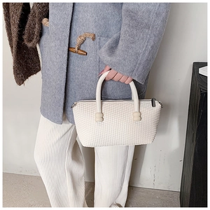 Close-up of beige woven texture handbag with unique double ball handle detail